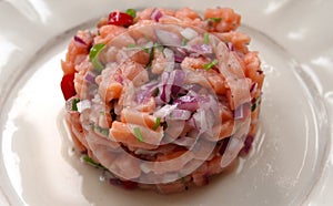 Salmon fish ceviche cooking ring serving on white plate close up. Traditional Peruvian dish