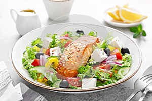 Salmon fish salad. Fresh vegetable greek salad with tomato, pepper, lettuce, olives, cucumbers, feta cheese and grilled salmon