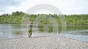 Salmon fisherman casting and reeling in the line