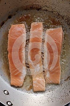 Salmon fried in oil in a pan