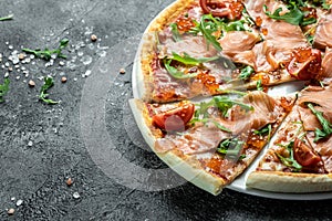 Salmon Italian Pizza with red caviar, tomatoes and aragula ready to eat on a dark background. banner, menu, recipe place for text