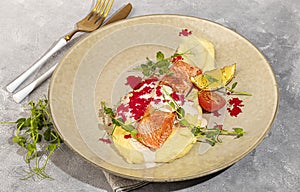 Salmon with mashed potatoes, topped with white sauce and garnished with caviar and pea sprouts