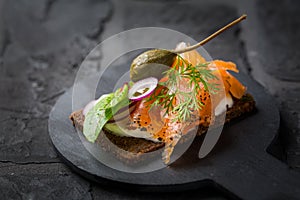 Salmon open sandwich on Pumpernickel bread with vegetables, herbs and soft cheese