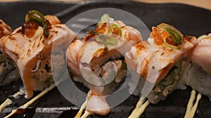 Salmon Oyako Spicy roll consist of crispy salmon skin is wrapped with sushi rice, topped with half broiled Aburi Salmon with spicy