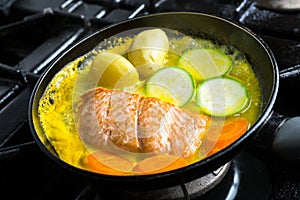 Salmon in pan with vegetables in citrus marinade