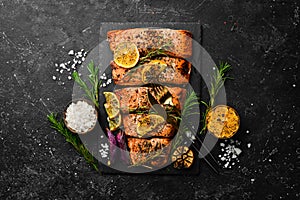 Salmon. Pieces of grilled fish on a black stone background. Recipe. Seafood.