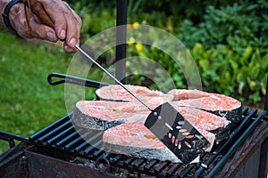 Salmon preparation process on wooden grill. Grilled fish steaks on fire. Top view