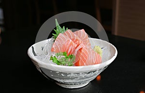 Salmon raw slice or salmon sashimi in Japanese style fresh serve on ice with fresh wasabi on black table