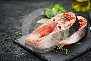 Salmon. Raw trout fish steak with herbs on black slate background. Cooking, seafood. Healthy eating