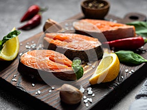 Salmon. Raw trout and red fish steak served with herbs, lemon and olive oil on a wooden board