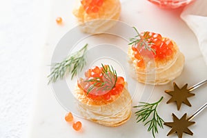 Salmon red caviar toast. Christmas canape or toast with red caviar on white plate on light background. Idea to xmas snack. Gourmet