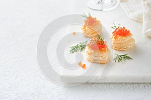 Salmon red caviar toast. Christmas canape or toast with red caviar on white plate on light background. Idea to xmas snack. Gourmet