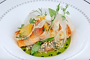 Salmon red fish fillet cooked with fresh green salad leafs close-up isolated on white plate