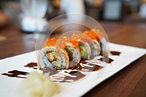 Salmon Roll - A plate of grilled salmon roll with avocado and foie gras, topped with ikura roe and sweet sauce.
