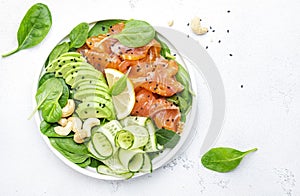 Salmon salad for ketogenic diet with avocado, spinach, cucumber, cashew nuts. Low-carbohydrate lunch rich in healthy fats. White