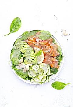 Salmon salad for ketogenic diet with avocado, spinach, cucumber, cashew nuts. Low-carbohydrate lunch rich in healthy fats. White