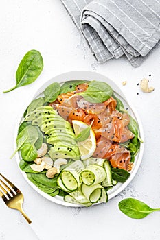 Salmon salad for ketogenic diet with avocado, spinach, cucumber, cashew nuts. Low-carbohydrate lunch rich in healthy fats. White