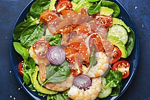 Salmon salad for ketogenic diet with shrimp, avocado, spinach, cucumber, tomato, cashew nuts, sesame. Low-carbohydrate lunch rich