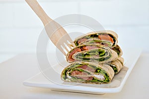 Salmon salad sandwich on a white plate. Roll lavash sandwich with red fish and lettuce. Thin mexican tortilla. Festive