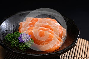 Salmon sashimi on black plate with parsley leaf. Japanese food style
