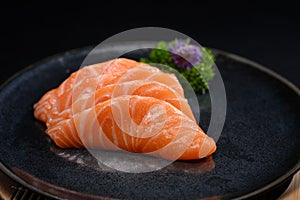 Salmon sashimi on black plate with parsley leaf. Japanese food style