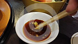 salmon sashimi in deeped in soy sauce bowl with chopstick. Japanese fusion food, Asian cultures. Healthy food, light diet concept