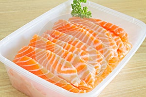 Salmon Sashimi in a plastic box container with parsley on the side