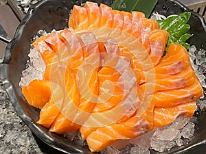 Salmon Sashimi, raw salmom sliced serving with ice on black bowl, eating with soy sauce and wasabi. Japanese traditional food