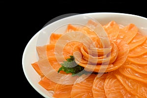 Salmon sashimi serve on flower shape on ice white bowl boat on black isolated background