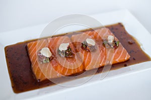 Salmon sashimi with soy sauce on white plate on white background.
