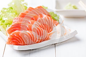 Salmon sashimi on white dish and wood background