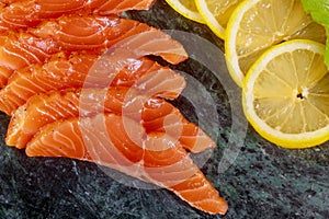 Salmon slices with herbs on marble plate background