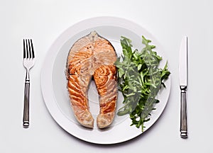 Salmon steak with arugula on plate