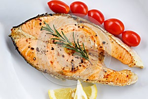 Salmon steak with herbs and spices rosemary lemon tomato on plate background - Close up cooked salmon fish fillet steak seafood