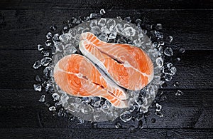 Salmon steak on ice on black wooden table top view