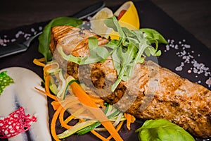 Salmon steak with lemon greens and sauce on stone with salt