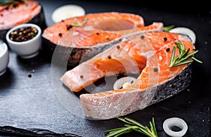 salmon steak, pepper and salt, herbs on black stone concrete table, copy space top view