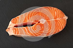 Salmon steak raw fish prepared for cooking. Top view on black slate table.