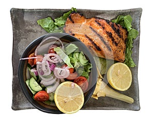Salmon steak with a salad and lemon is isolated on white