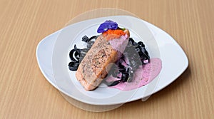 Salmon steak with Squid ink pasta beetroot cream sauce frying fish roe tobiko.