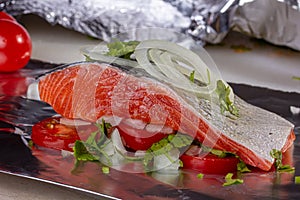 Salmon steak with tomatoes and onions for baking in aluminum foil