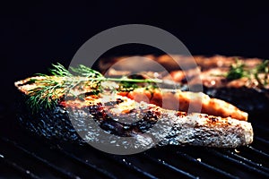 Salmon steaks cooking on barbecue grill. Food background with ba