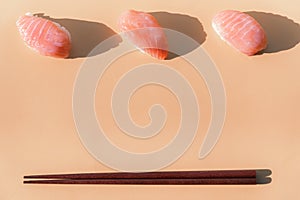 Salmon sushi closeup with chopsticks on beige background