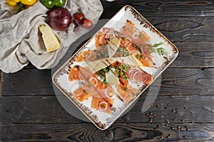 Salmon or trout carpaccio with herbs, capers, onions and cheese. Red fish cold appetizer