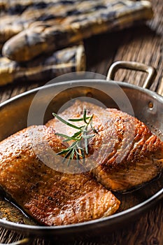 Salmon. Two juicy salmon steaks in roast pan with herb decoration on rustic oak table