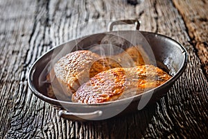 Salmon. Two juicy salmon steaks in roast pan with herb decoration on rustic oak table