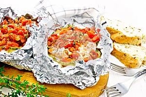 Salmon with vegetables in foil on white board