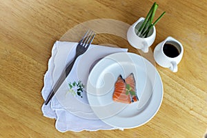 Salmon in white dish and fork on wooden