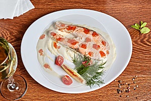 Salmon with white sauce, decorated with red caviar, cherry tomatoes, dill and a slice of lemon with red pepper