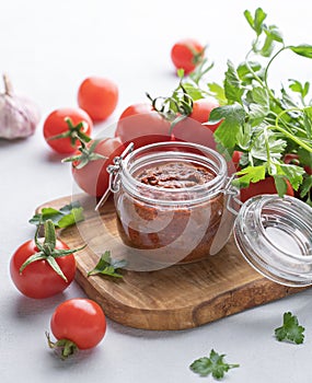 Salsa sauce is a traditional Mexican sauce with tomatoes and hot peppers on a light background with fresh herbs close up